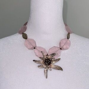 Silver flower pendant on a pink quartz necklace.
